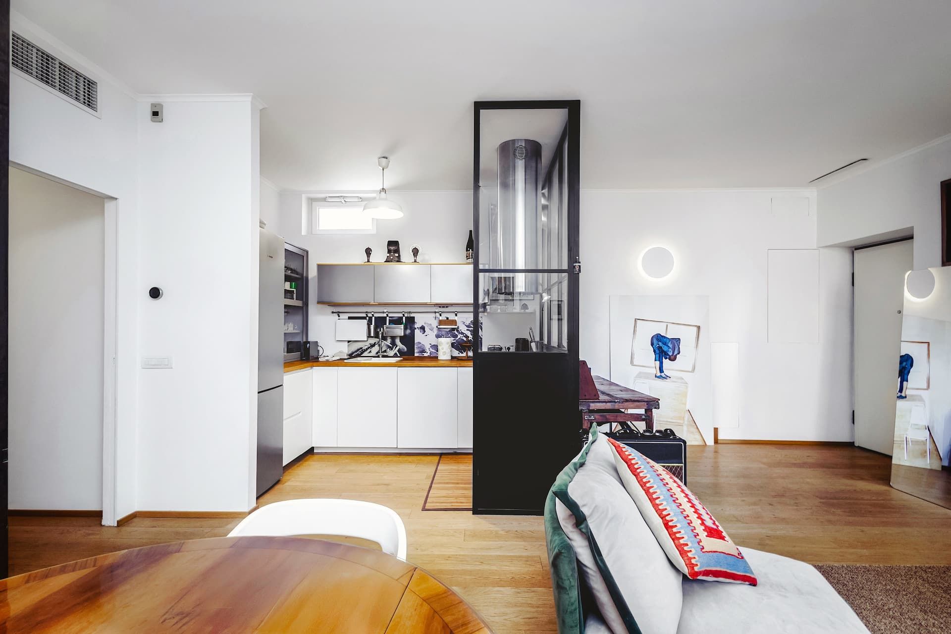 Spazi connessi, luce continua. La zona giorno è suddivisa da eleganti vetrate interne che separano cucina, area living e spazio di lavoro, mantenendo una continuità visiva e una luminosità uniforme in tutto l’ambiente.