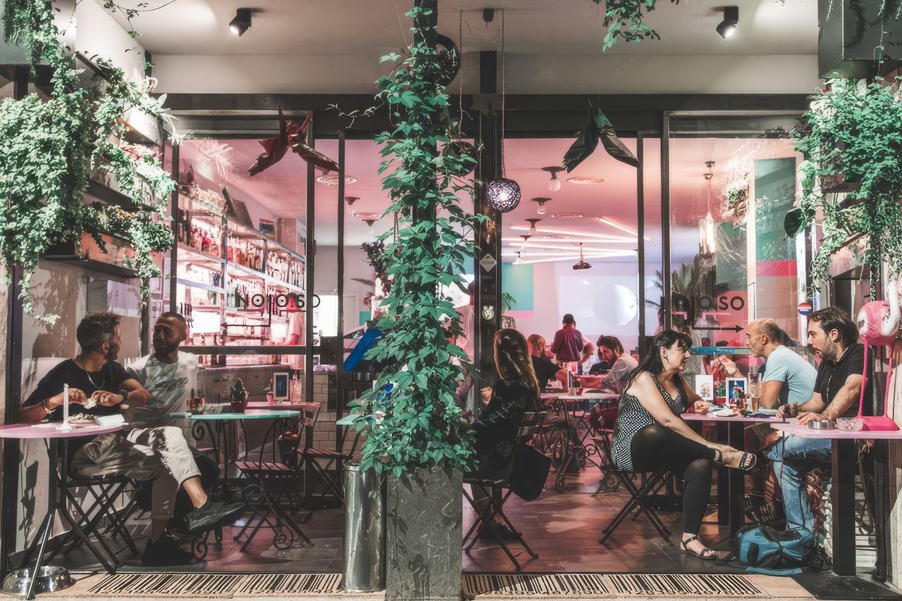 Il cocktail bar Noloso, nel quartiere NoLo di Milano, tra piante rampicanti e luci al neon rosa all'ora dell'aperitivo.